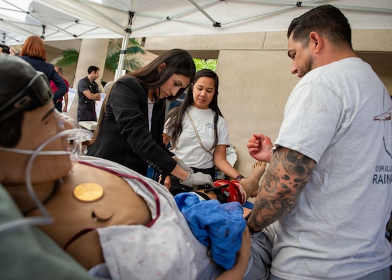 Enrique Navarro, right, a bioskills and simulation training center specialist at Naval Medical Center San Diego, shows Nina Mendoza, a student at Alliant University, how to apply a tourniquet on an interactive patient simulator during the 41st Academic Research Competition and Innovation Day at NMCSD, April 10. NMCSD employs more than 5,500 active-duty military personnel, civilians, and contractors in Southern California to deliver exceptional care afloat and ashore. (U.S. Navy photo by Mass Communication Specialist 1st Class Marcus L. Stanley)