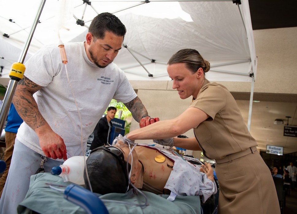 Enrique Navarro, left, a bioskills and simulation training center specialist at Naval Medical Center San Diego, shows Ens. Maria Schlichtholz, a nurse resident at NMCSD, how to perform a tracheostomy on an interactive patient simulator during the 41st Academic Research Competition and Innovation Day at NMCSD, April 10. NMCSD employs more than 5,500 active-duty military personnel, civilians, and contractors in Southern California to deliver exceptional care afloat and ashore. (U.S. Navy photo by Mass Communication Specialist 1st Class Marcus L. Stanley)
