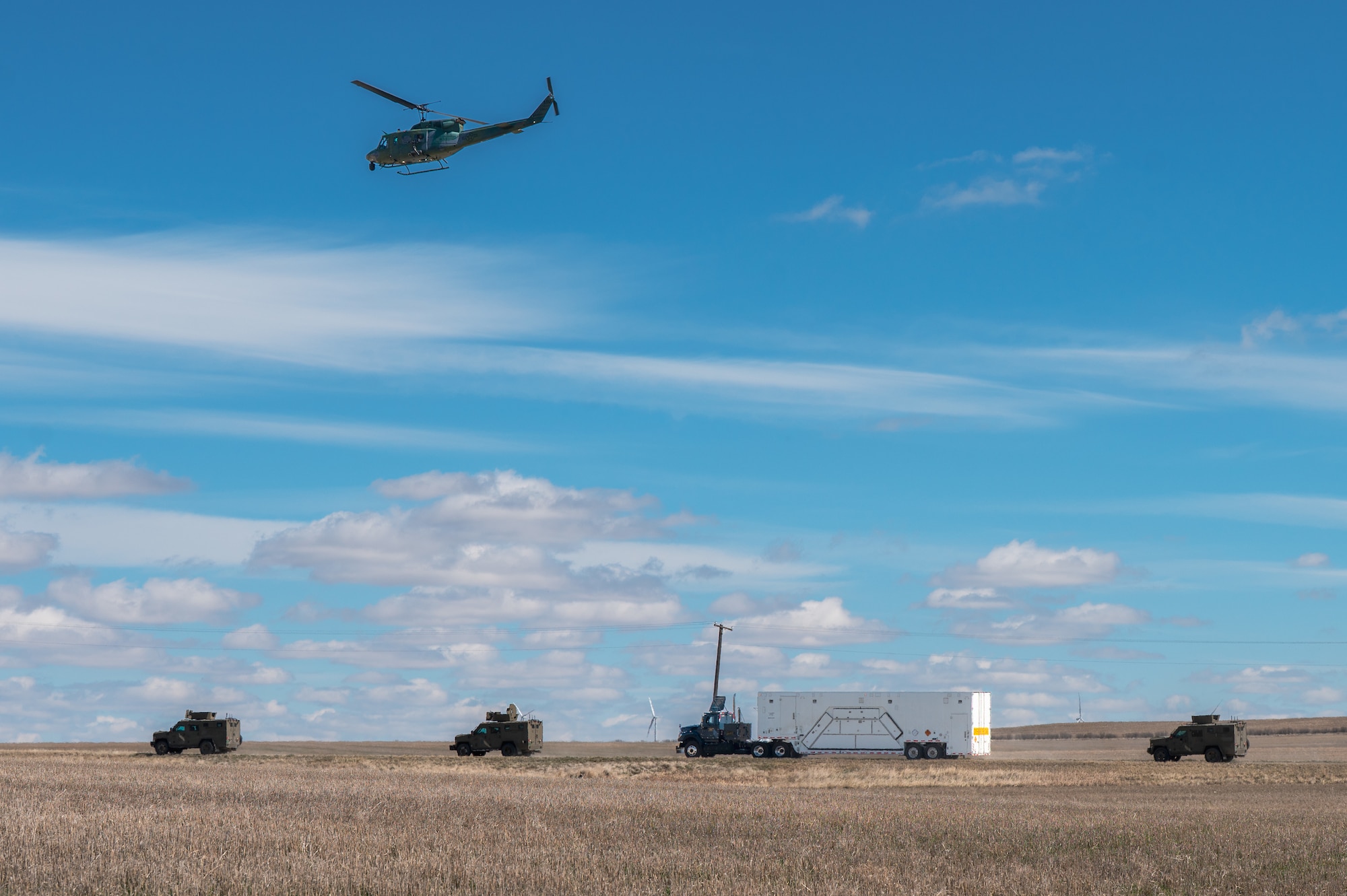 A convoy with a helicopter flying over.