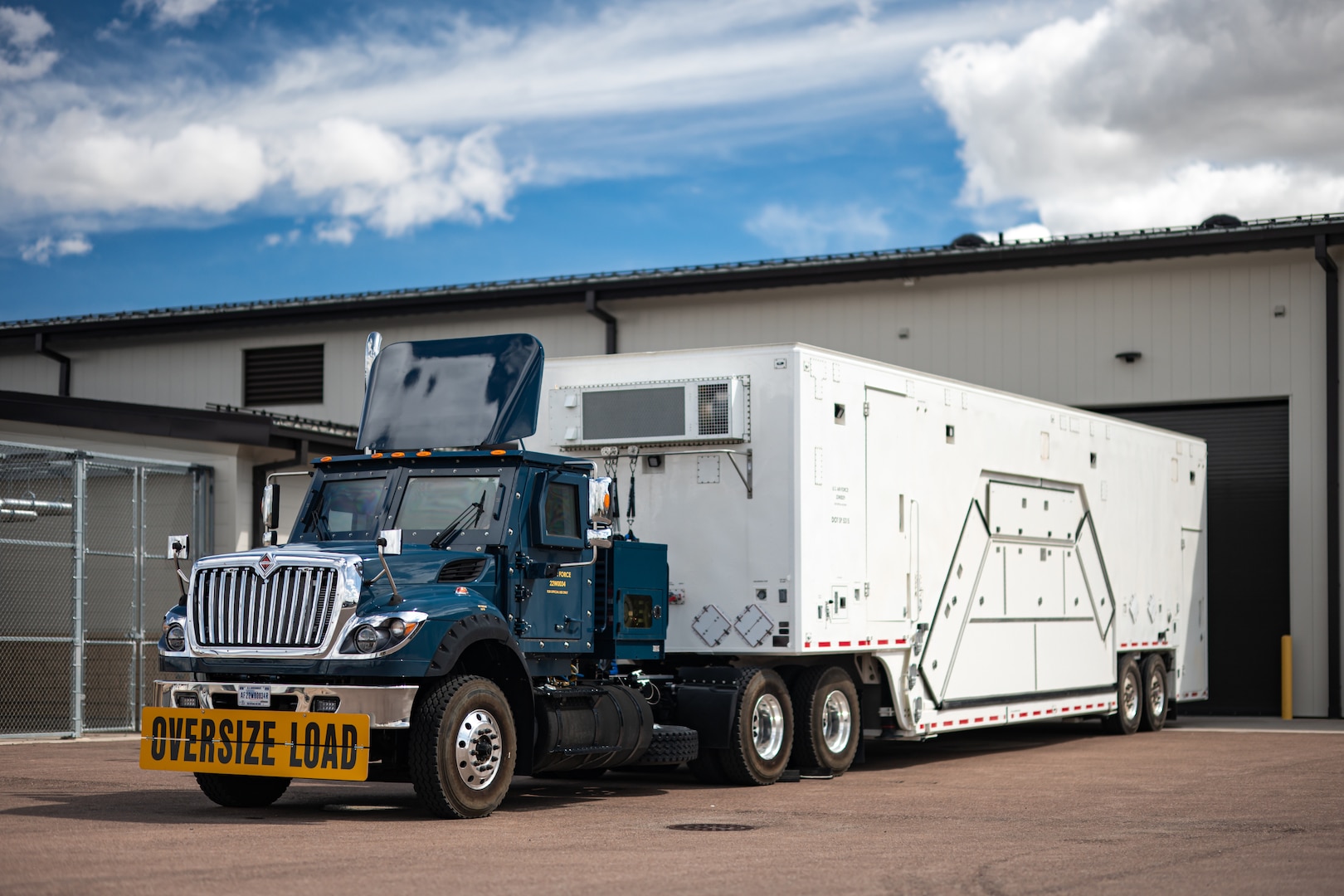 A payload transporter replacement is parked in front of a building