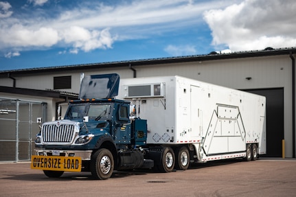 A payload transporter replacement is parked in front of a building