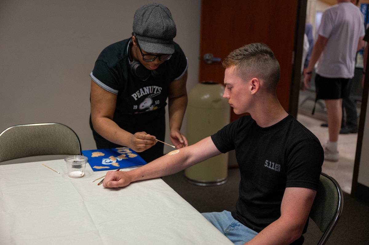 A member of the Angelo State University theatre department applies makeup to a U.S. Marine from the Marine Corps Detachment Goodfellow during a joint emergency response exercise at Mathis Field, San Angelo Regional Airport, San Angelo, Texas, April 15, 2026. The realistic injuries were used to simulate casualties and enhance training for participating agencies. (U.S. Air Force photo by Senior Airman James Salellas)