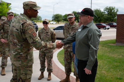 U.S. Air Force Maj. Gen. Roy W. Collins, Air Education Training Command deputy commander, coins Brian Stansburry, 17th Force Support Squadron employee, outside the Cressman Dining Facility at Goodfellow Air Force Base, Texas, April 10, 2026. Stansburry and the rest of the DFAC team were recognized for winning the John Hennessy Food Service Excellence Award. (U.S. Air Force photo by Senior Airman Brian Lummus)