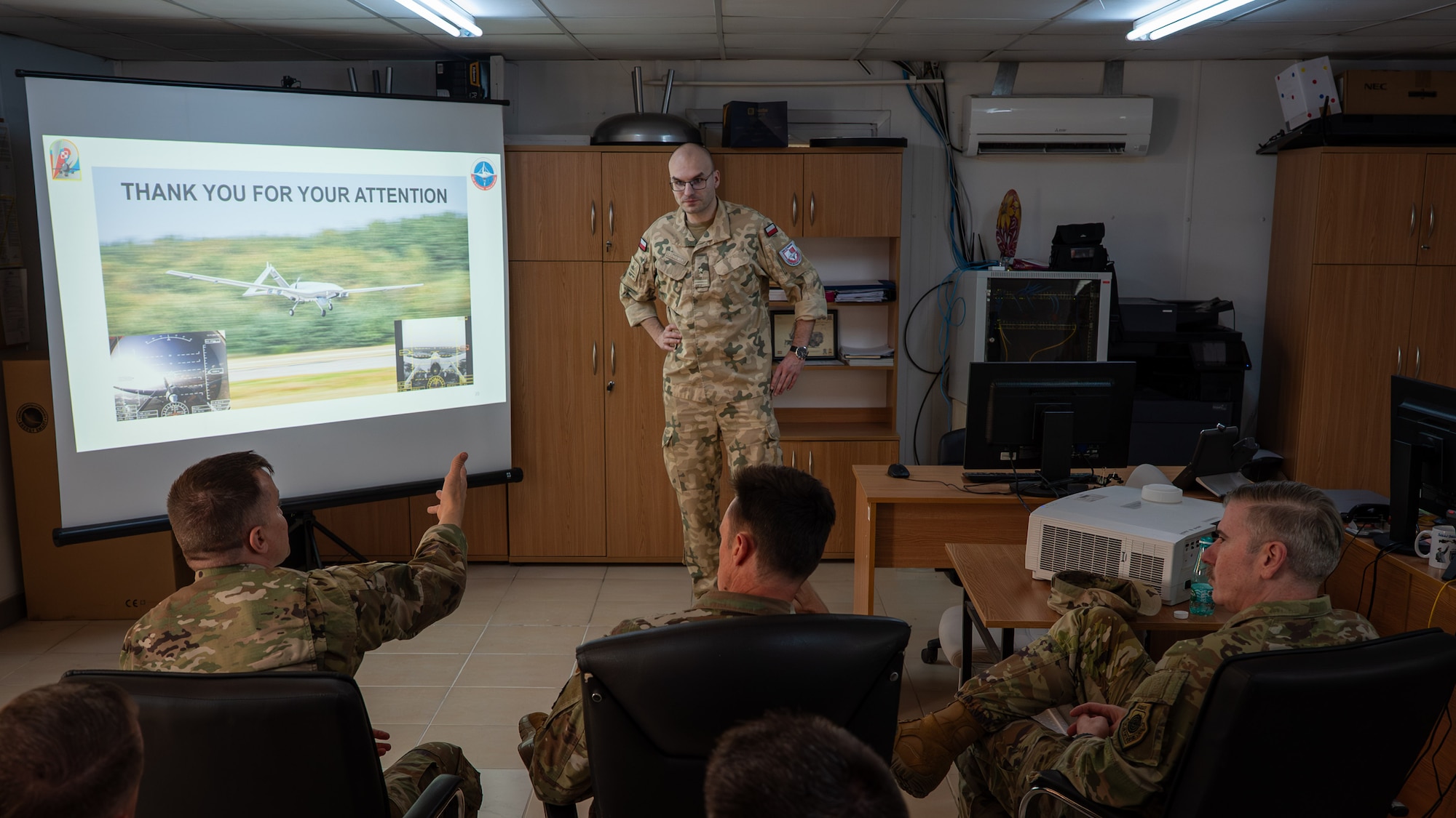 A polish service member talking to a group of US Airmen