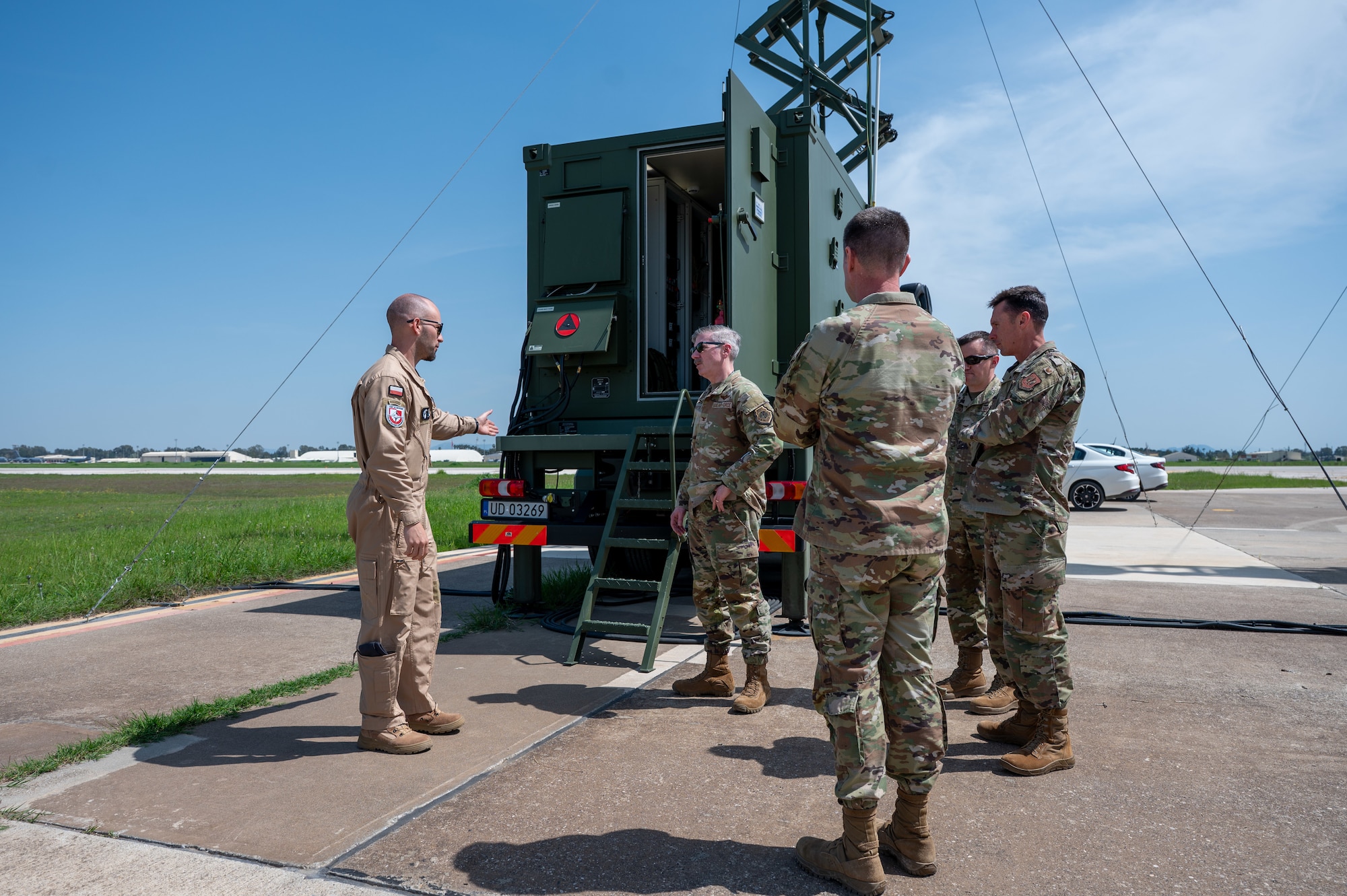 Four people talking next to a group control station