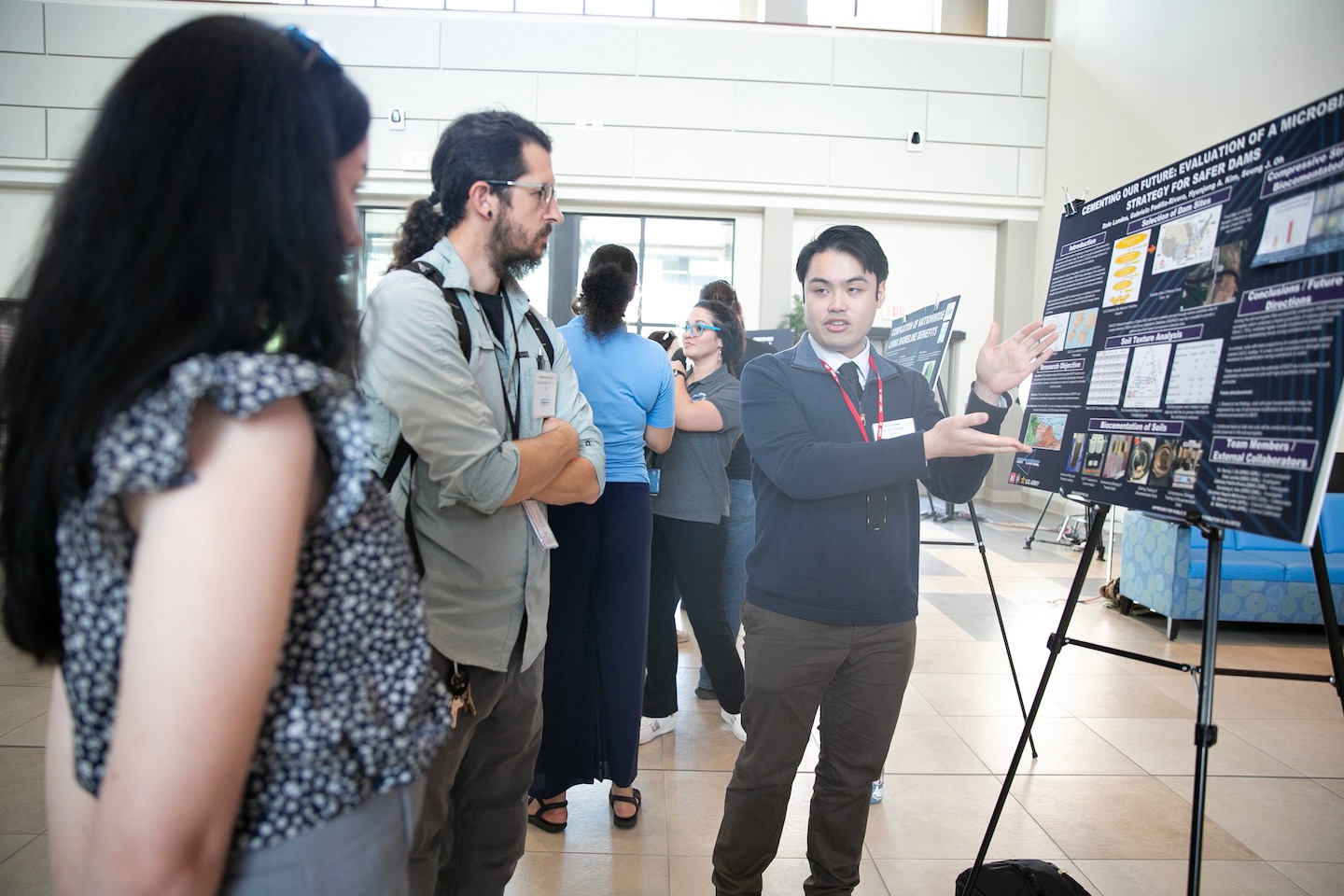 Several people in a buildign lobby gathered around a man with a poster and having a discussion.