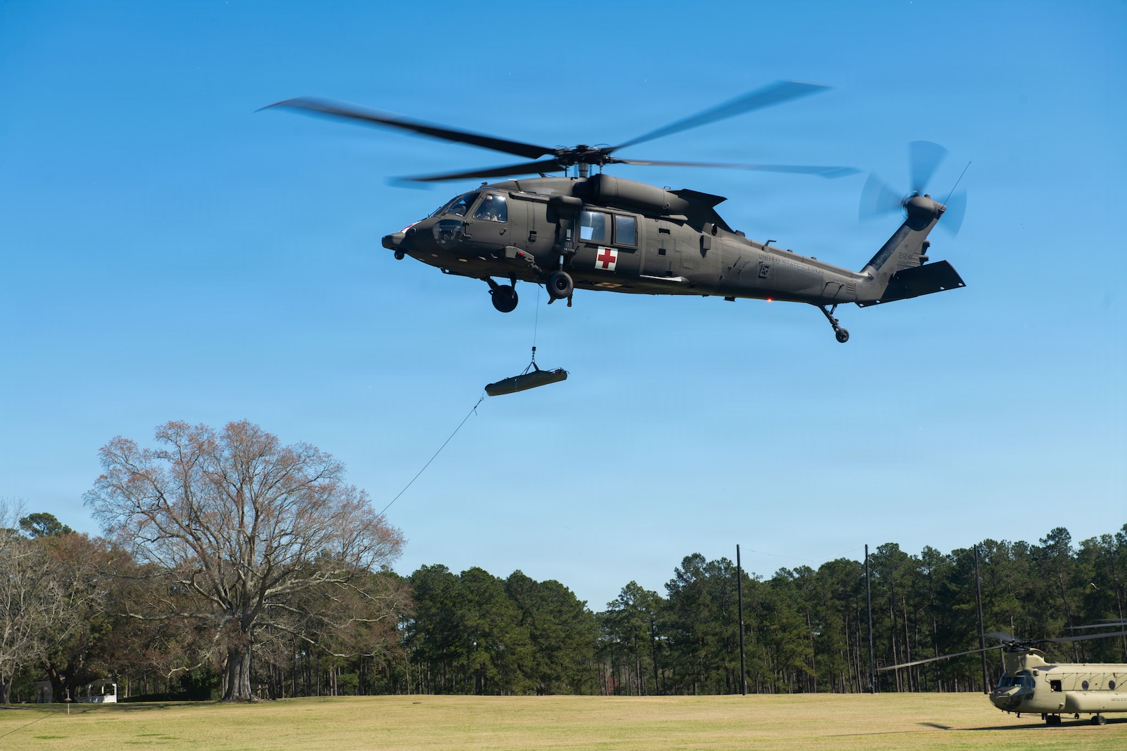 A UH-60 Black Hawk assigned to the Mississippi Army National Guard raises a medical litter carrying a medical practice dummy during exercise Sentry South 26-2 at Camp Shelby Joint Forces Training Center, Mississippi, March 2, 2026. Sentry South 26-2 is a large force employment exercise focused on major combat operations and joint maritime opportunities in a contested or degraded operational environment. Sentry South 26-2 applies joint and combined warfighting doctrine against realistic and robust enemy integrated threat systems, all while under safe and controlled conditions. (U.S. Air National Guard photo by Staff Sgt. Nicholas Swift)
