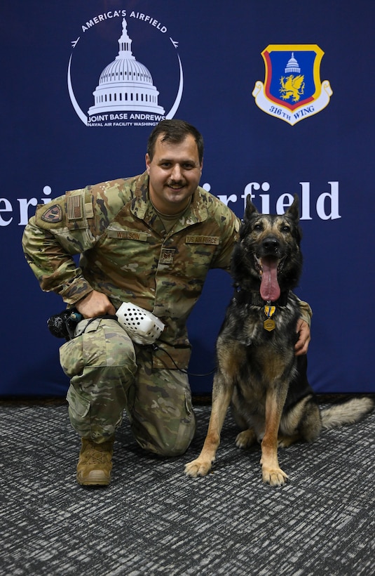U.S. Air Force Staff Sgt. Ryan Willson, 316th Security Support Squadron military working dog handler, celebrates with Military Working Dog Howoard, assigned to the 316th SSPTS, during Howoard’s retirement ceremony.