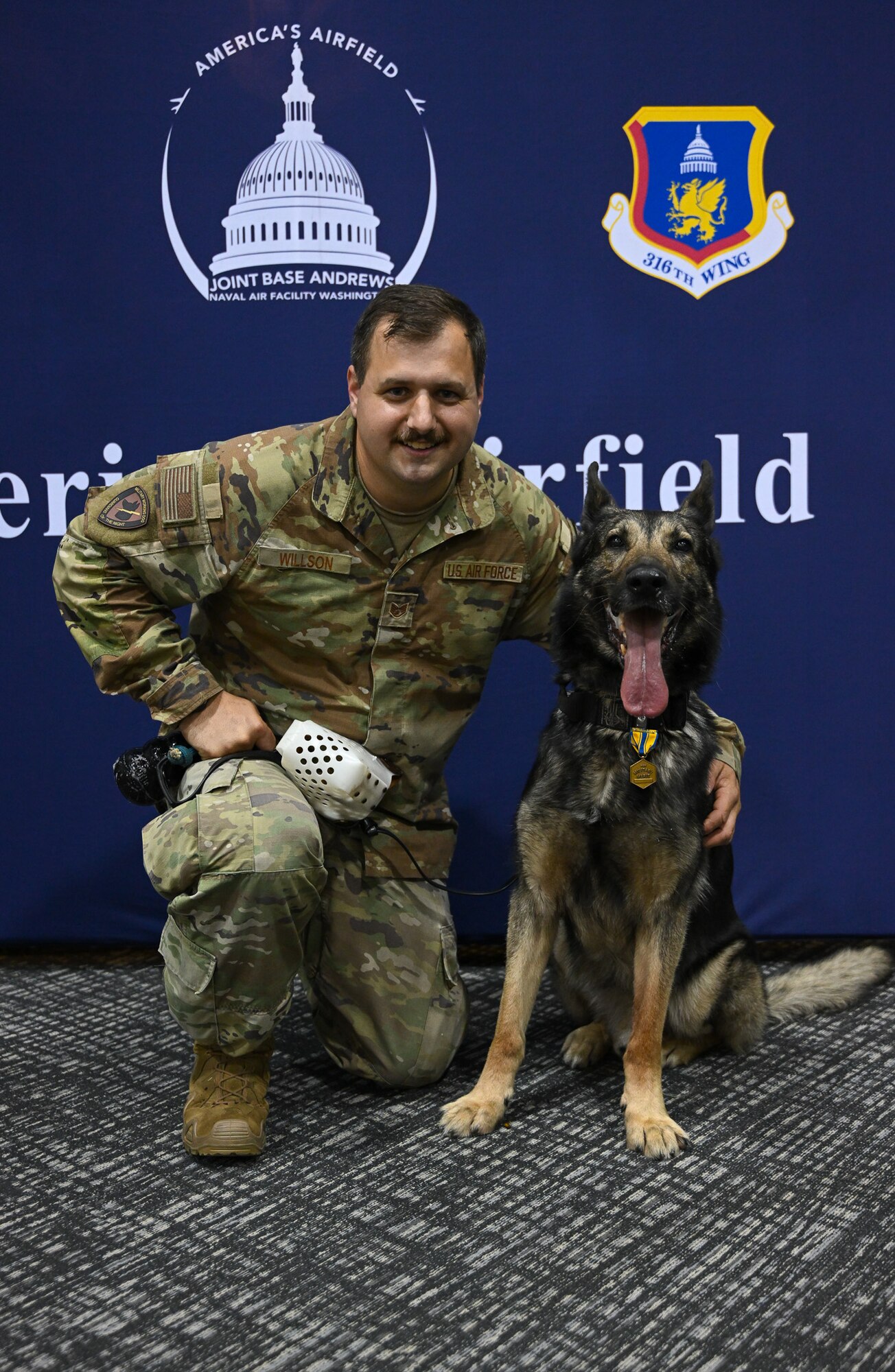 U.S. Air Force Staff Sgt. Ryan Willson, 316th Security Support Squadron military working dog handler, celebrates with Military Working Dog Howoard, assigned to the 316th SSPTS, during Howoard’s retirement ceremony.
