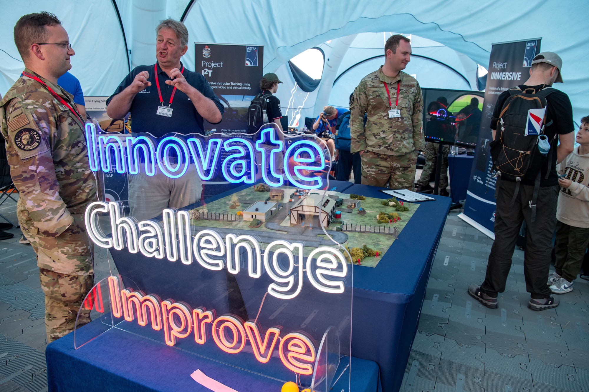 A sign reading “INNOVATE CHALLENGE IMPROVE” is displayed in the RAF Astra tent during the Royal International Air Tattoo (RIAT)