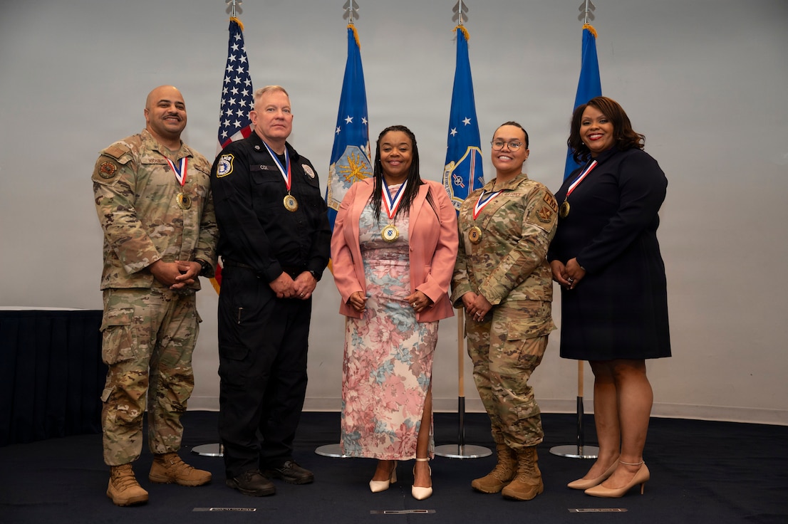 From left: U.S. Air Force Master Sgt. Michael Hooper, first sergeant with the 11th Civil Engineer Squadron; Sgt. 1st Class Robert Cox, operations flight chief with the 11th Security Forces Squadron; Cheryl Grant, security assistant for reports and analysis with the 11th SFS; Master Sgt. Devin Garcia, financial management flight chief with the 11th Comptroller Squadron; and Welth Cooper, commodities and services flight chief with the 11th Contracting Squadron, gather during the Air Force District of Washington annual award ceremony at Joint Base Anacostia-Bolling, Washington, D.C., April 9, 2026. The event honored outstanding performance and achievements across AFDW. (U.S. Air Force photo by Airman 1st Class Arlene Carrara)