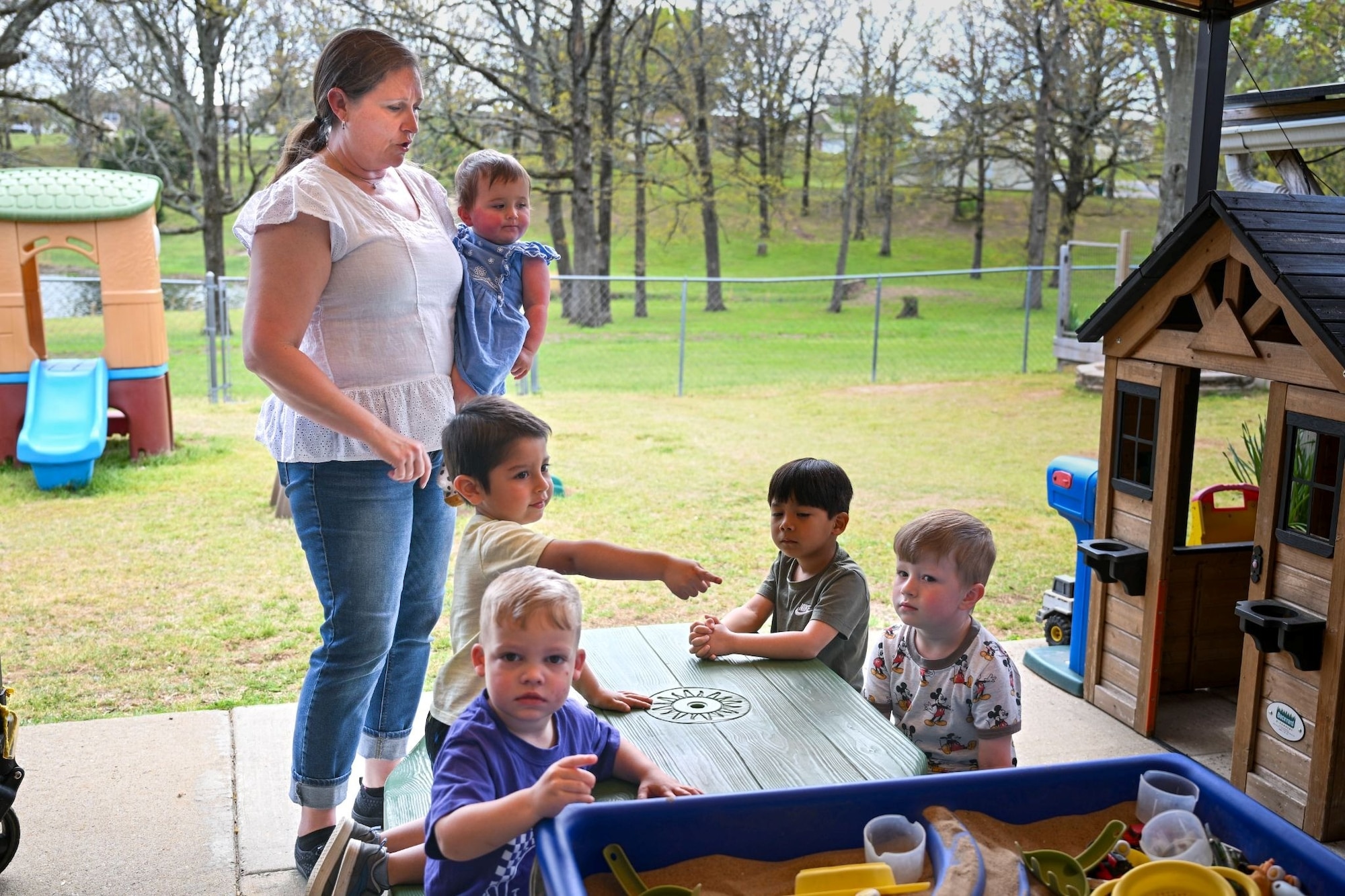 A woman interacts with five small children.