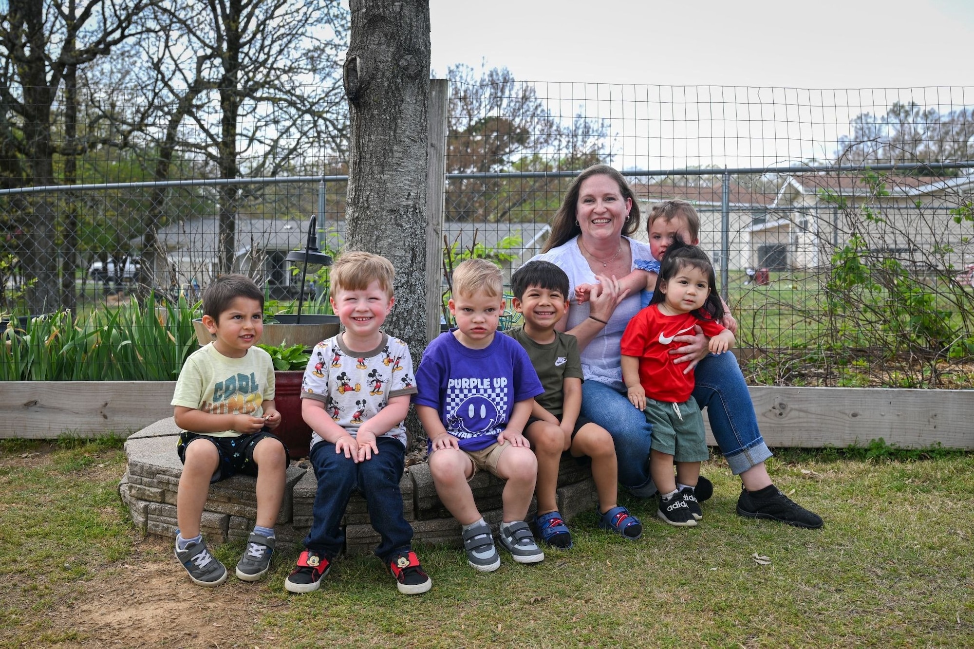 A woman poses for a photo with six small children.