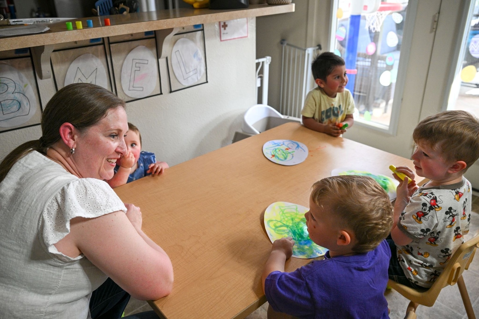 A woman interacts with four small children.