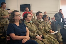 A photo of civilian workers and Airmen listening to a presentation.