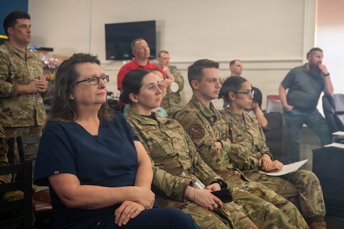 A photo of civilian workers and Airmen listening to a presentation.
