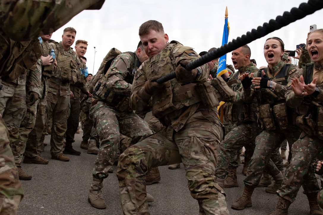 Soldiers gather in parallel lines and cheer as soldiers pull a rope in the center.
