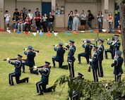 The drill team performs outside while students watch.