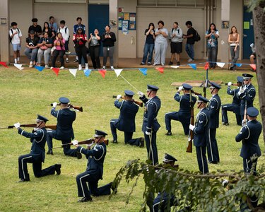 The drill team performs outside while students watch.