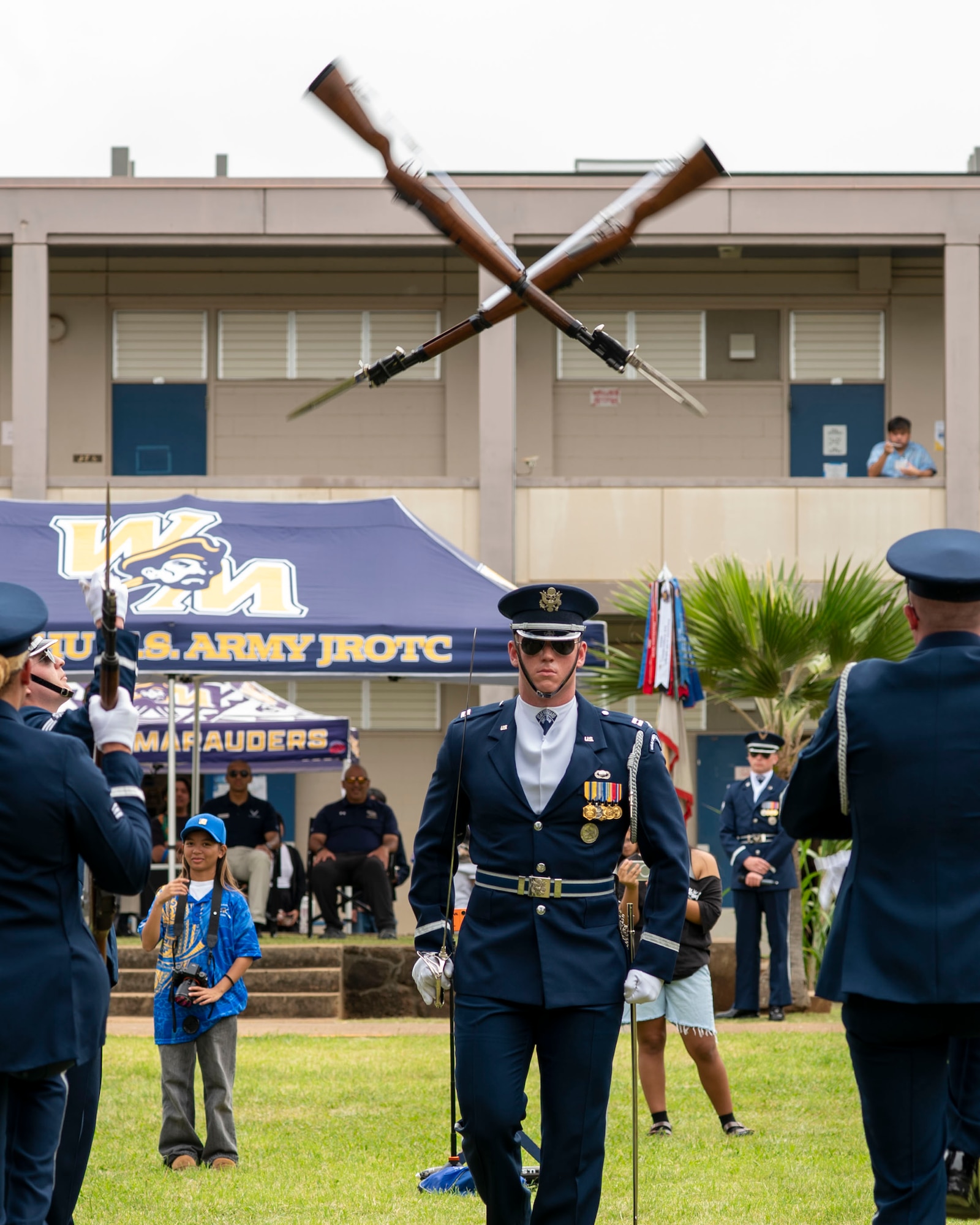 An Airman walks under two rifles thrown over his head.