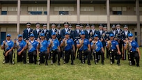 Airmen and JROTC cadets pose for a group photo in blue uniforms.