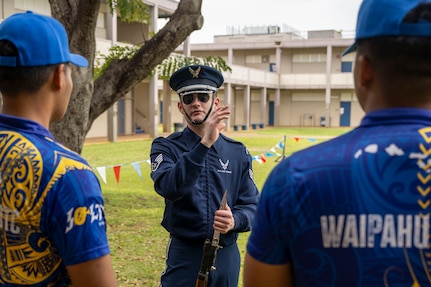 An Airman stands outside while speaking to two JROTC cadets.