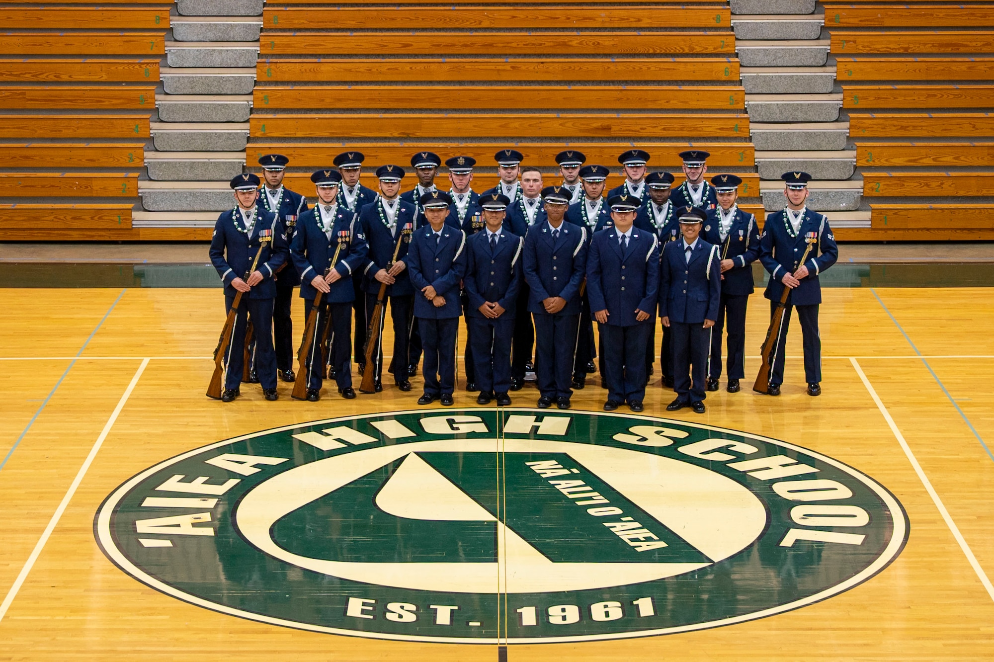 Airmen pose for a group photo in a gym.
