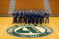 Airmen pose for a group photo in a gym.