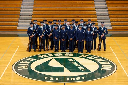 Airmen pose for a group photo in a gym.
