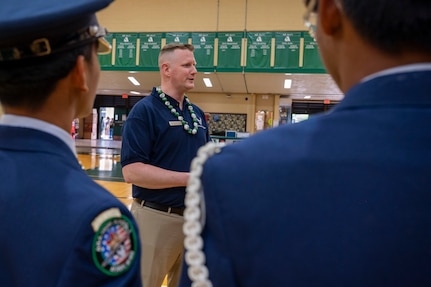 Airman stands between two students while speaking to them.