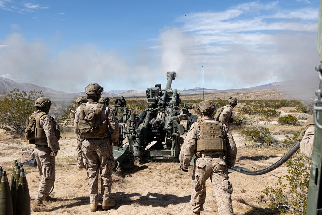 U.S. Marines with Kilo Battery, 3rd Battalion, 11th Marine Regiment, 1st Marine Division, fire a 155mm round from an M777A2 howitzer during a battery movement to contact exercise at Marine Corps Air Ground Combat Center, Twentynine Palms, California, March 6, 2026. The exercise allows Marines to conduct fire missions while continuously displacing to maintain the unit's survivability and culminating in the defense of the battery through direct fire engagements and crew-served weapons employment. (U.S. Marine Corps photo by Lance Cpl. Emilio Murphy)