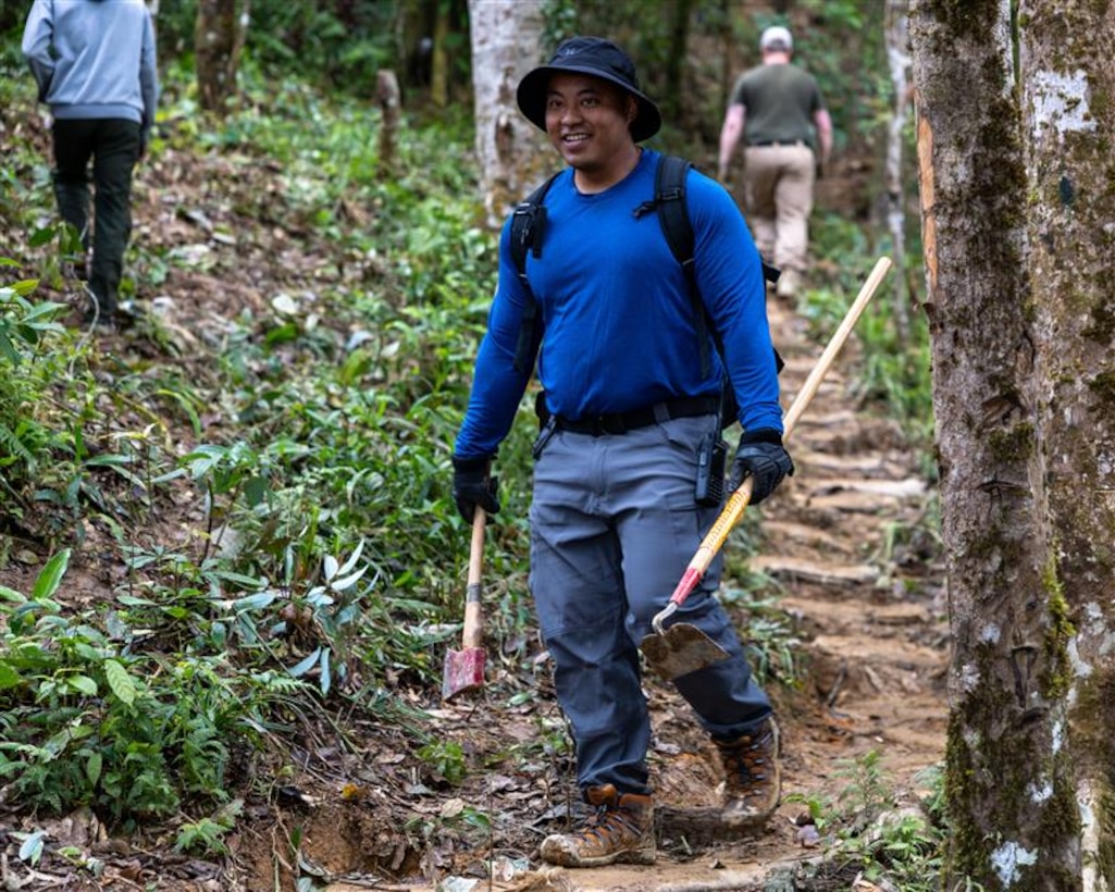 U.S. Army Staff Sgt. Somvang Xayphengsy, center, a recovery NCO, assigned to a Defense POW/MIA Accounting Agency recovery team, helps carry tools during a recovery mission in Laos, March 8 2026.