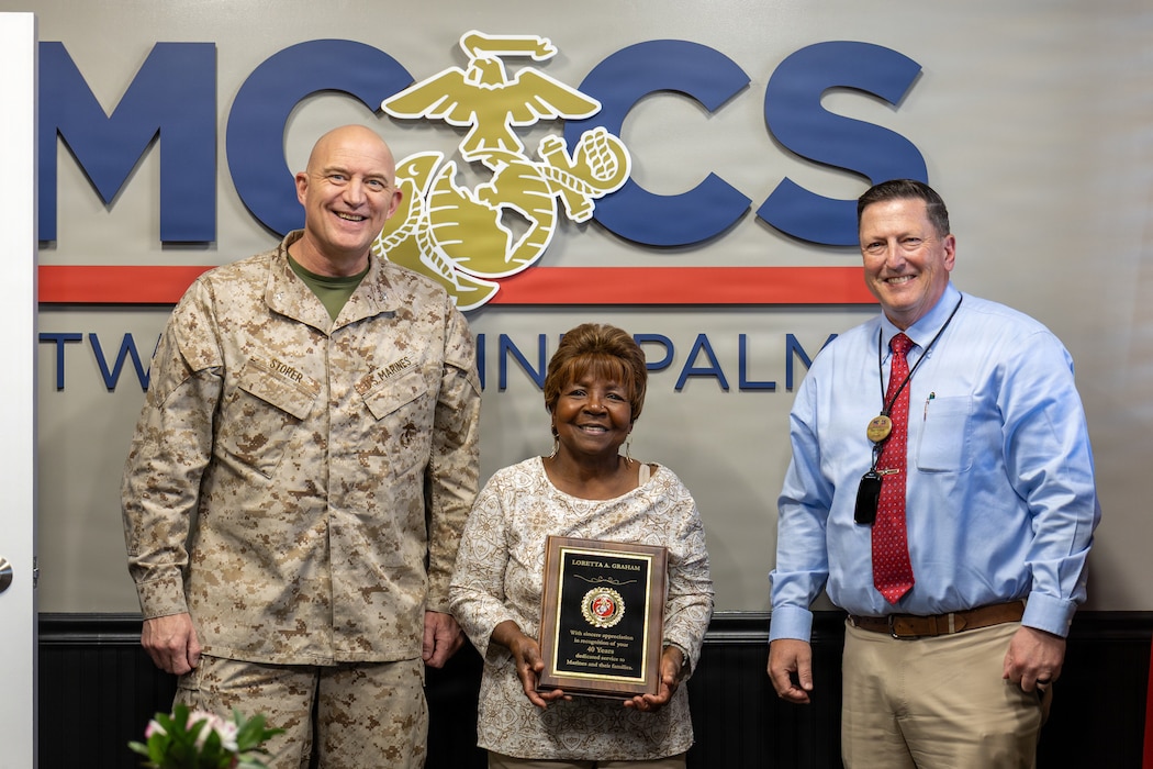 U.S. Marine Corps Col. Ronald Storer, chief of staff with Marine Air Ground Task Force Training Command, Marine Corps Air Ground Combat Center poses for a photo with Ms. Loretta Graham, an employee with Marine Corps Community Service Twentynine Palms, at MCAGCC, Twentynine Palms, California, Feb. 12, 2026. Graham was recognized for her 40 years of continuous support and dedication to Marines and civilians aboard the installation. (U.S. Marine Corps photo by Lance Cpl. Jozef P. Majewski)