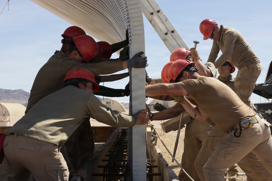U.S. Air Force Airmen with 820th Rapid Engineer Deployable Heavy Operational Repair Squadron Engineers, brace a wall during a joint project at Camp Wilson, Marine Corps Air Ground Combat Center, Twentynine Palms, California, March 17, 2026. U.S. Air Force RED HORSE airmen built a hangar to provide durable infrastructure for aircraft operations and support future mission requirements at the installation. (U.S. Marine Corps photo by Lance Cpl. Lainey Brummett)