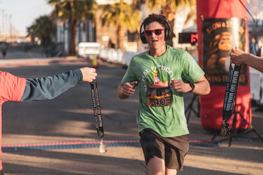 A participant receives a medal after completing the Mojave Half Marathon at Marine Corps Air Ground Combat Center, Twentynine Palms, California, March 14, 2026. The Mojave Half Marathon marked the first ever 13.1-mile race aboard the installation, it challenged runners to improve their physical fitness as they ran through the desert, while encouraging camaraderie within the community of MCAGCC. (U.S. Marine Corps photo by Lance Cpl. Emilio Murphy)