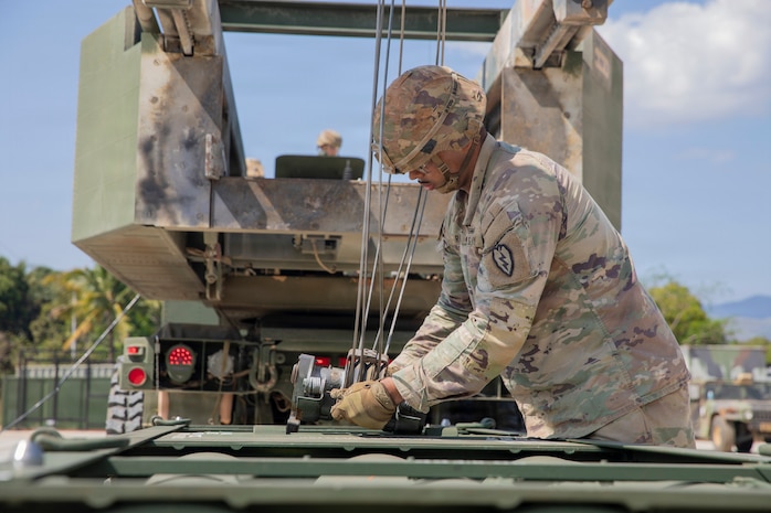 U.S. Army Staff Sgt. Jose Rivera, a multiple launch rocket system/high mobility launch rocket system (HIMARS) crewmember assigned to 2nd Battalion, 11th Long Range Fires Battalion, hooks a hoist onto the rocket pod during reload operations at Canantong, Laur, Neuva Ecija, Apr. 15, 2026.
