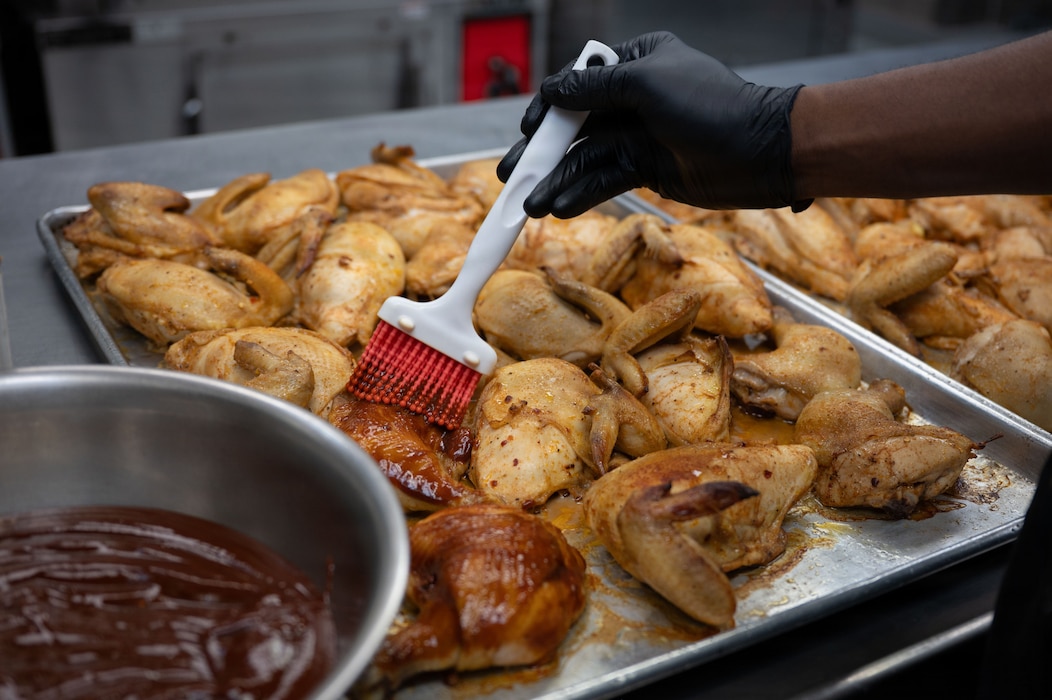 U.S. Air Force Airman Noah Kassim, 354th Force Support Squadron food services apprentice, glazes chicken at Eielson Air Force Base, Alaska, March 31, 2026.