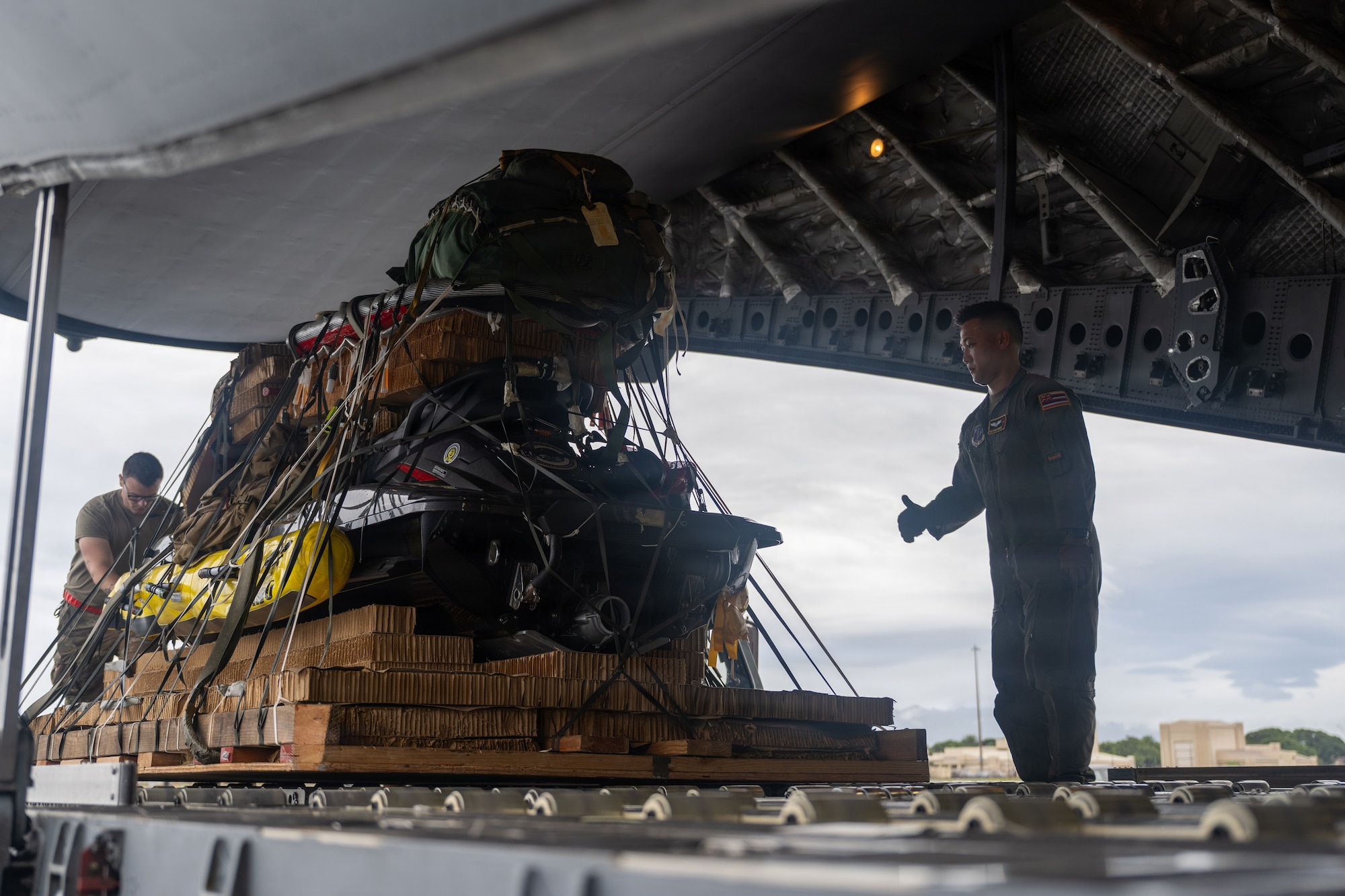 U.S. Air Force loadmaster and air transportation specialists move supplies and rafts onto a C-17 Globemaster III.