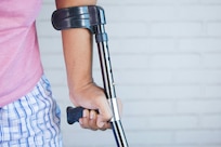 The left arm of a person using a crutch to walk.