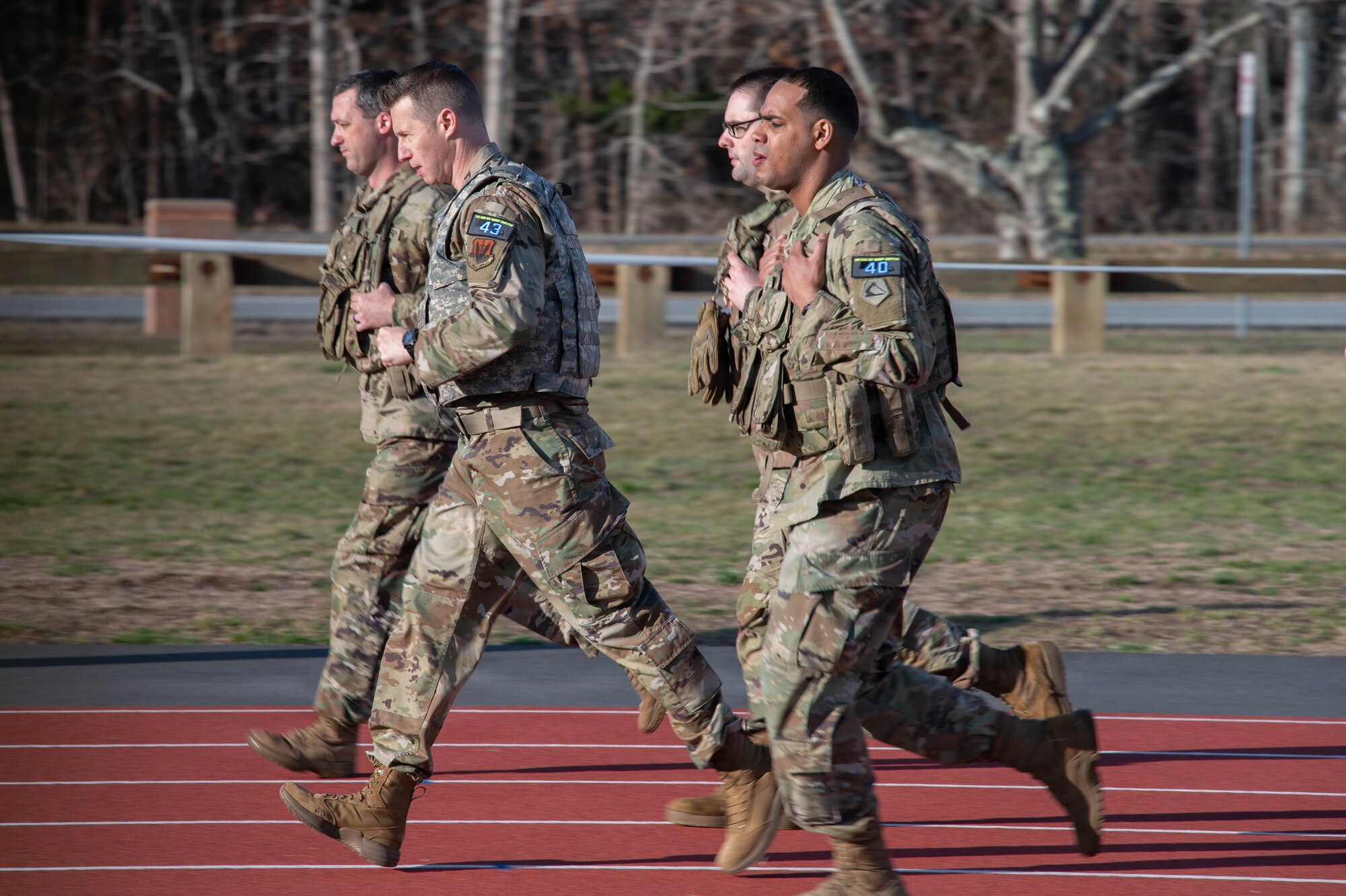 Airmen and Soldiers run on a track.