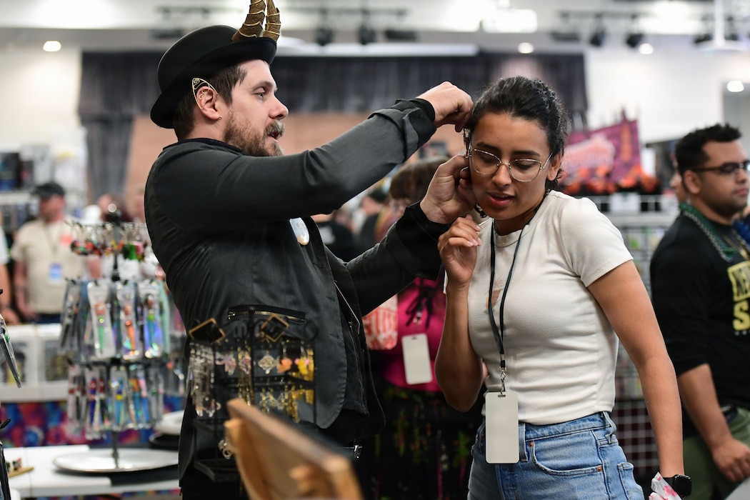 A man attaches earring jewelry to a woman's ear.