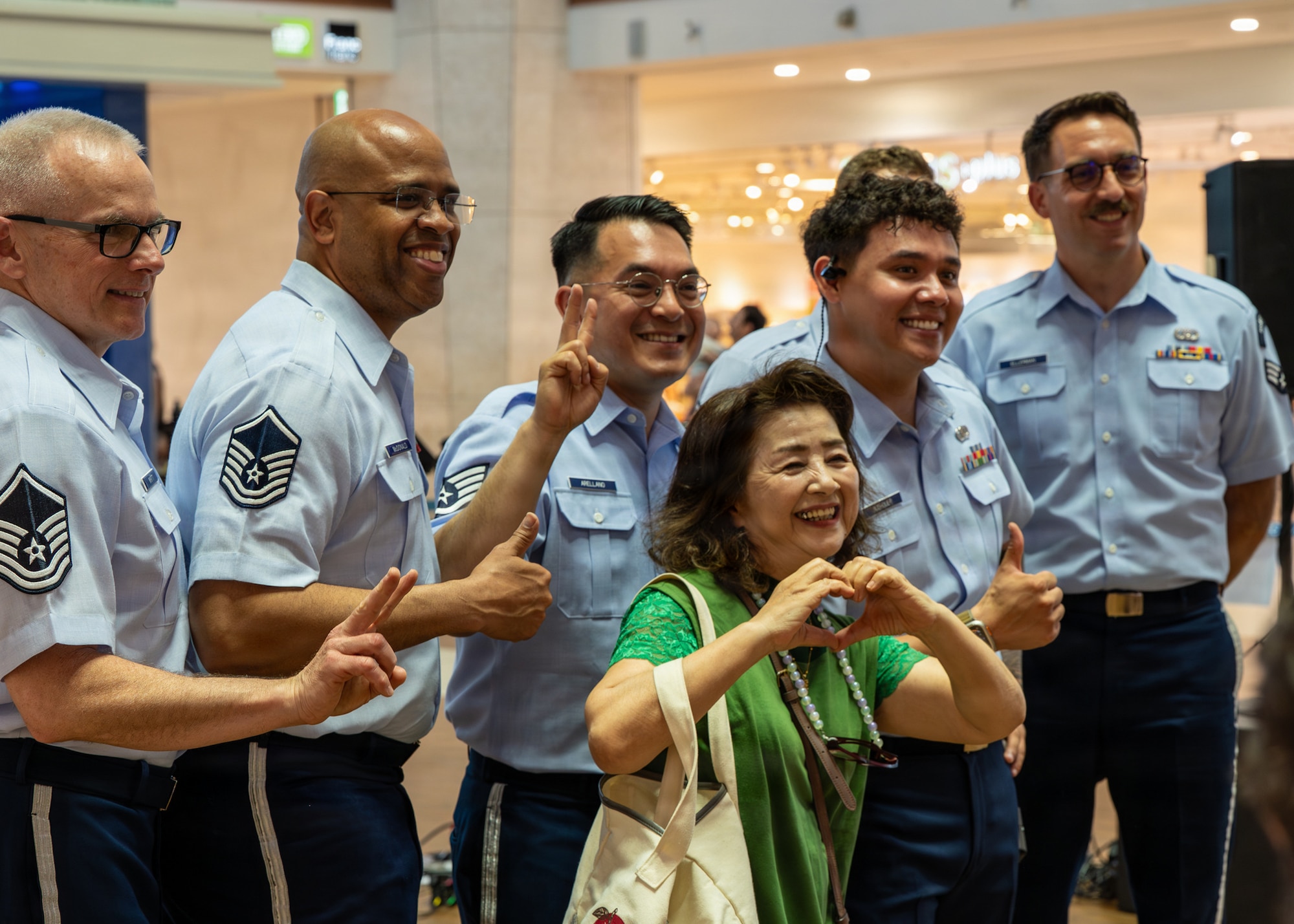 U.S. Air Force Airmen assigned to the U.S. Air Force Band of the Pacific pose with an Okinawan resident following a performance at a local mall in Kitanakagusuku, Okinawa, April 13, 2026.