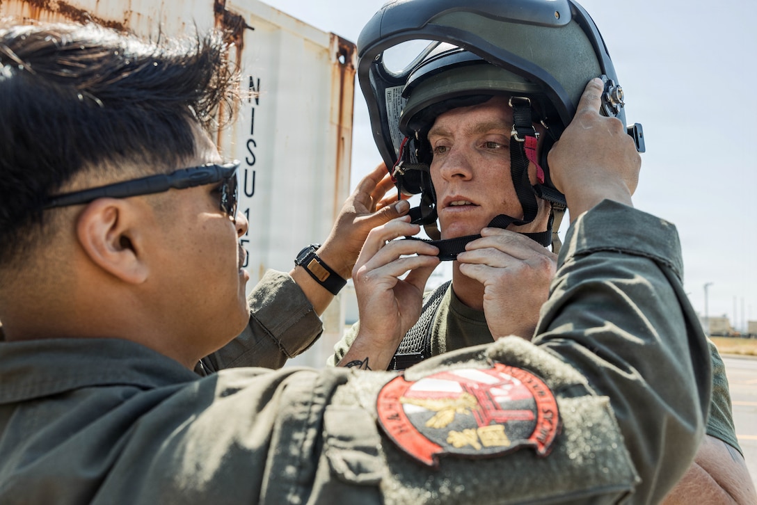 U.S. Marine Corps Sgt. Victor Perez, left, an explosive ordnance disposal technician with Headquarters and Headquarters Squadron (HHS), Marine Corps Air Station Iwakuni, dons on a EOD-10 Bomb Suit on Sgt. Riley Hummell, an EOD technician with HHS, MCAS Iwakuni and a native of Pennsylvania, during improvised explosive device training at MCAS Iwakuni, Japan, April 8, 2026. The MCAS Iwakuni EOD team conducts live-fire practical applications to refine individual and collective technical proficiency in the employment of IED distribution tools and techniques. (U.S. Marine Corps photo by Cpl. Sarah Grawcock)