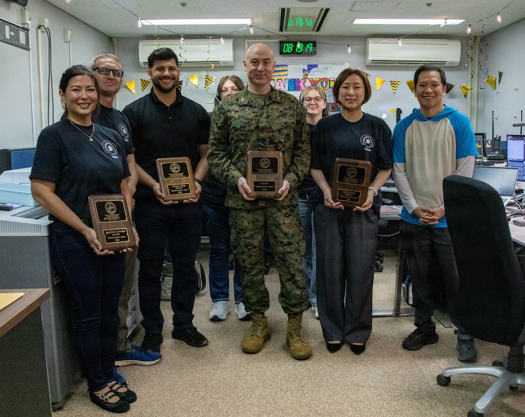 U.S. Marine Corps Col. Kenneth Rossman, center, the commanding officer of Marine Corps Air Station Iwakuni and a native of Pittsburgh, Pennsylvania, and emergency dispatch telecommunicators with Headquarters and Headquarters Squadron (HHS), MCAS Iwakuni, pose for a photo during National Public Safety Telecommunicator Week on MCAS Iwakuni, Japan, April 14, 2026. National Public Safety Telecommunicators Week is held in April to honor public safety personnel for their dedicated service. This is the 2nd year in a row that MCAS Iwakuni Public Safety Telecommunicators have been recognized at a unit and individual level within Marine Corps Installations Pacific. (U.S. Marine Corps photo by Lance Cpl. Maikeyla Reyes)