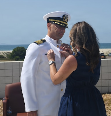 Capt. Damian Storz, is presented with his Command-at-Sea pin by his wife, during the Military Sealift Command hospital ship USNS Mercy (T-AH 19) Medical Treatment Facility (MTF), welcomed their new commanding officer, Capt. Damian Storz, during a ceremony at the Island Club, on Naval Air Station North Island, today. Storz assumed command from Capt. Charles Dickerson, who served as the MTF commanding officer since 2024.