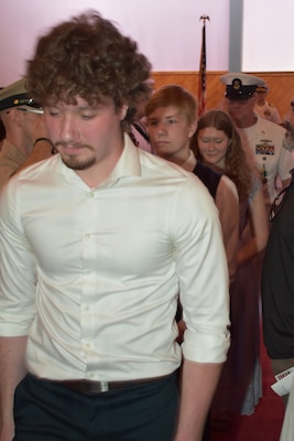 Master Chief Lindbeck follows behind his wife and their nine children as they exit the retirement ceremony.