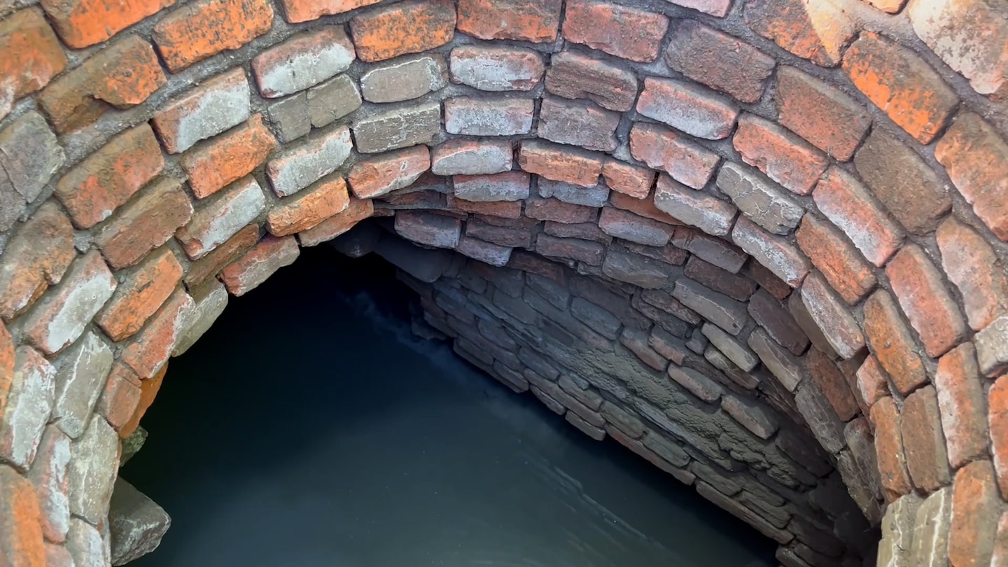 An arc of bricks with stagnat water at the bottom of the image.