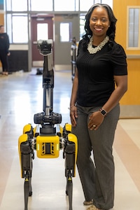 Dr. Crystal M. Ricks, the Supervisor of Gifted, Advanced Learning, Articulation, STEM & MESA, and Robotics Competition, poses with a Boston Dynamics robot dog