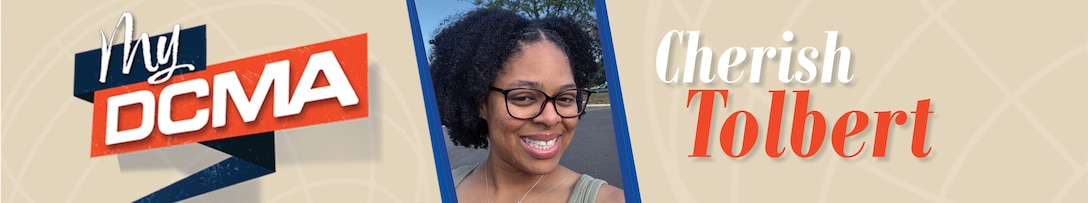 A smiling woman wears glasses and a green top