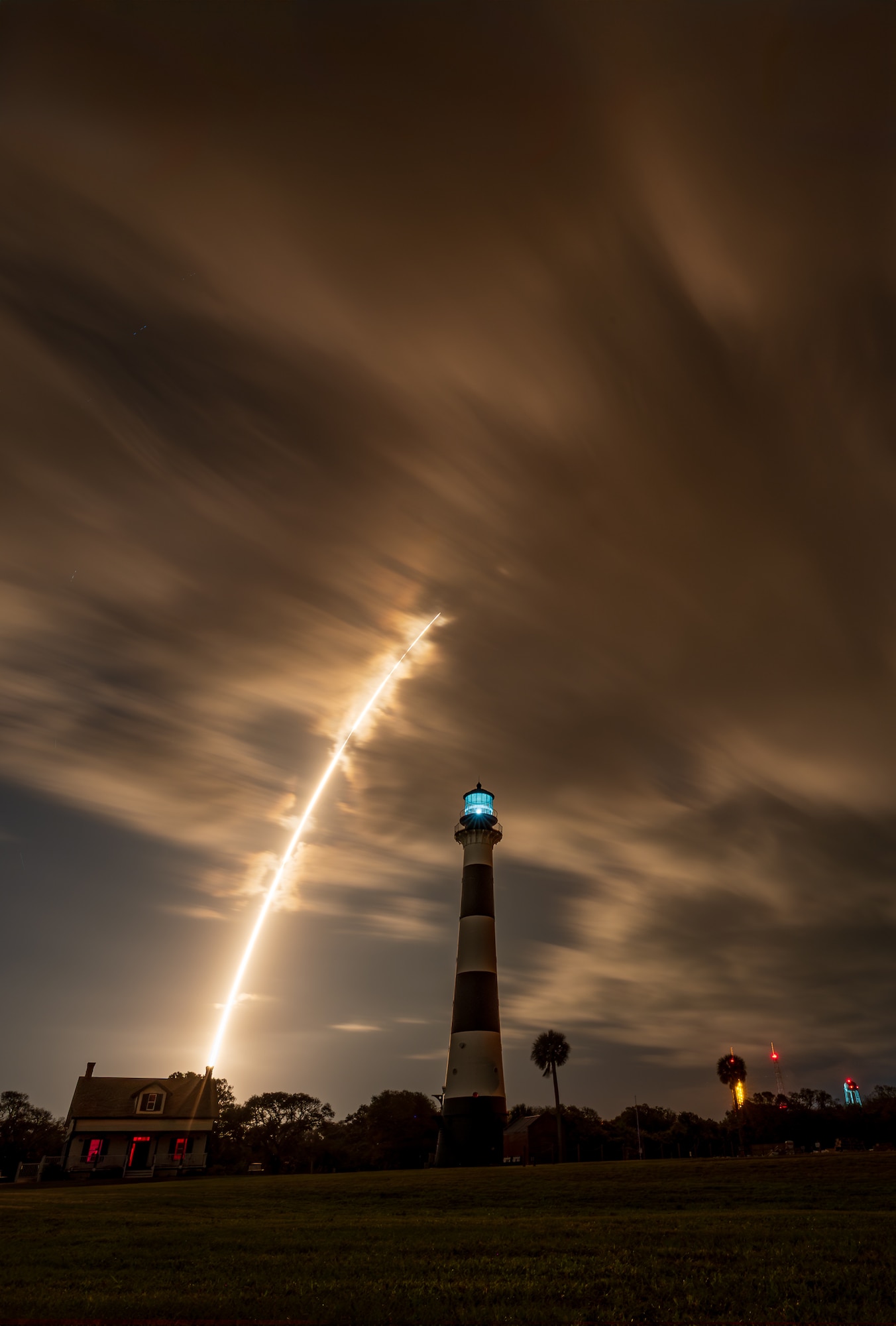 The historic Cape Canaveral Lighthouse, a mid-1800s beacon that once guided sailors with oil lamps and Fresnel lenses, stands watch as a Falcon 9 rocket streaks skyward carrying GPS III-8 on April 21, 2026. The launch of the final GPS III satellite symbolizes America’s leap from 19th-century maritime navigation to today’s space-based positioning, navigation and timing as the nation celebrates its 250th anniversary. (U.S. Space Force photo by Gwendolyn Kurzen)